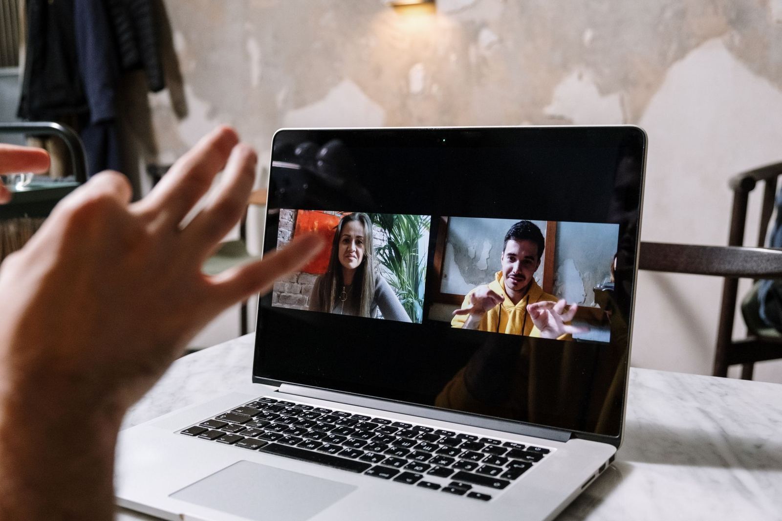Two people on a video call discussing content on a laptop