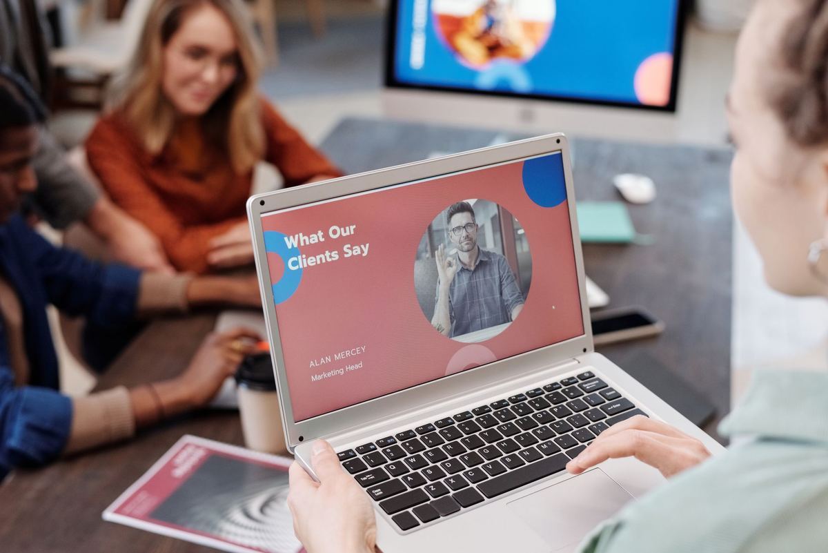 A person looking at a laptop screen while colleagues talk in the background