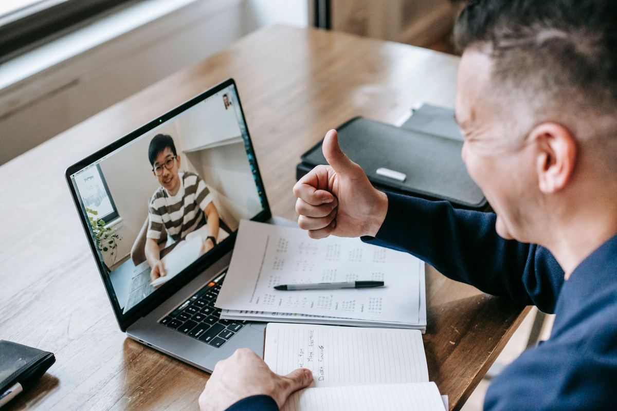 A man giving a thumbs up during a video call on a laptop