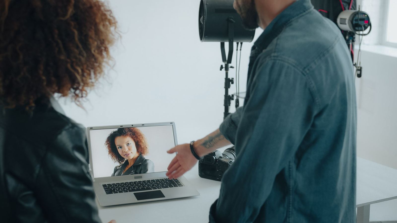 A photographer reviewing photos with a client on a laptop